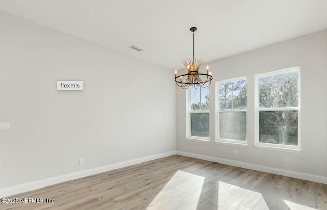 unfurnished dining area featuring a notable chandelier, vaulted ceiling, and light hardwood / wood-style floors