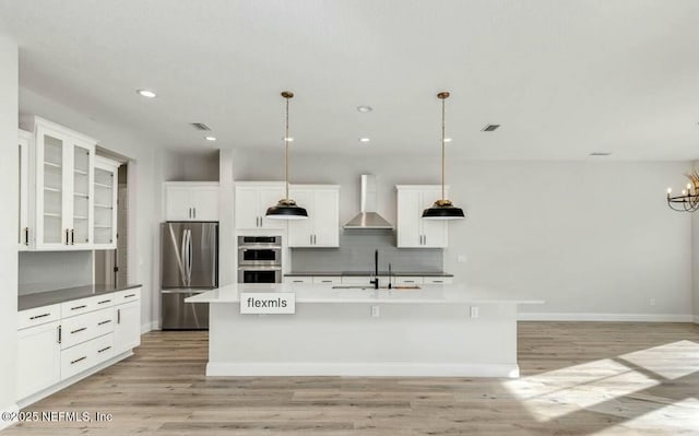 kitchen featuring sink, decorative light fixtures, stainless steel appliances, and wall chimney exhaust hood