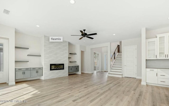 unfurnished living room with ceiling fan, a fireplace, and light hardwood / wood-style flooring