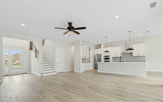 unfurnished living room featuring sink, ceiling fan, and light hardwood / wood-style flooring