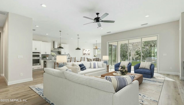 living room with ceiling fan and light hardwood / wood-style flooring