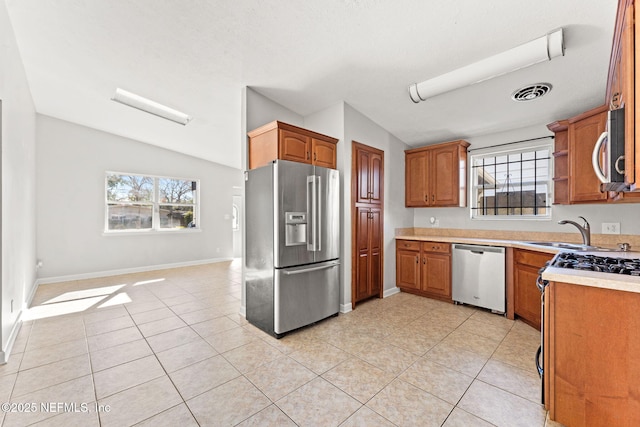 kitchen featuring lofted ceiling, stainless steel appliances, sink, and light tile patterned floors