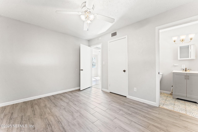 unfurnished bedroom with ceiling fan, connected bathroom, a textured ceiling, and light hardwood / wood-style floors