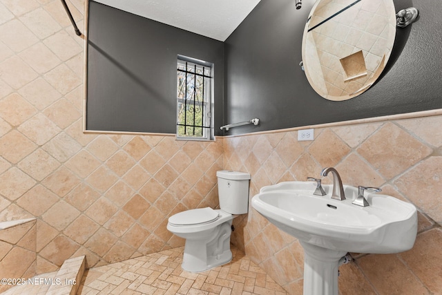 bathroom featuring toilet and tile walls