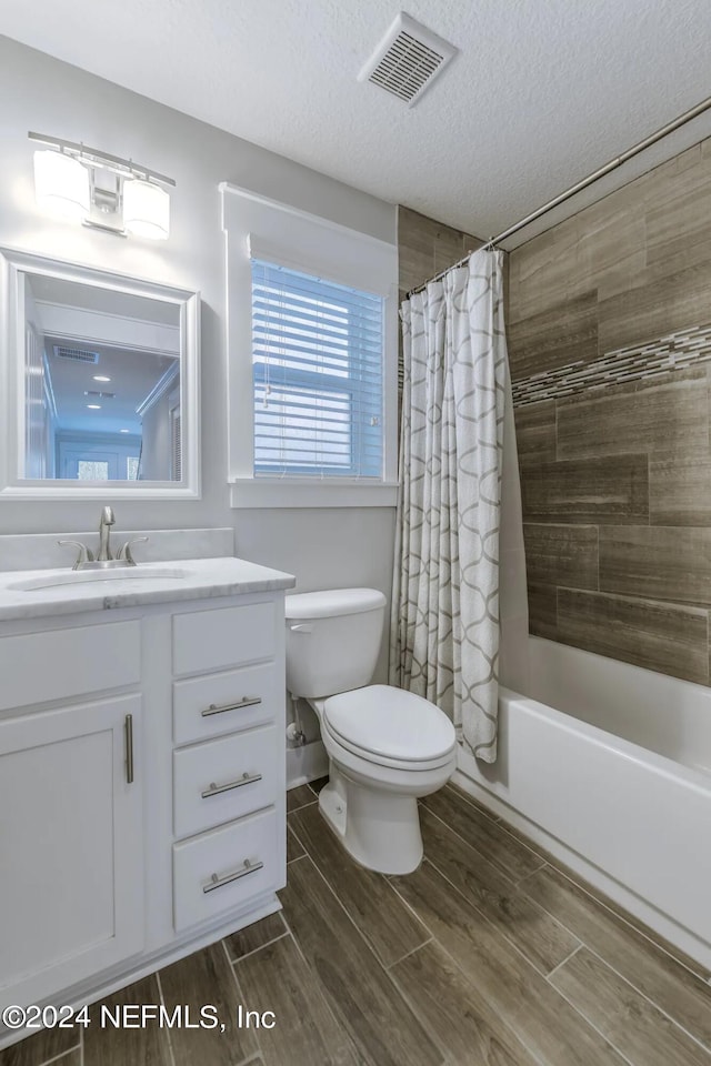 full bathroom with vanity, shower / tub combo, a textured ceiling, and toilet