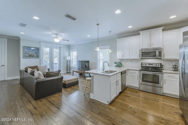 kitchen featuring decorative light fixtures, appliances with stainless steel finishes, a kitchen breakfast bar, kitchen peninsula, and white cabinets