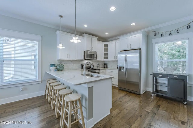 kitchen with white cabinetry, stainless steel appliances, tasteful backsplash, decorative light fixtures, and kitchen peninsula