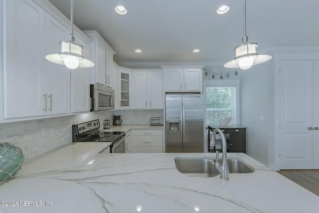 kitchen featuring pendant lighting, appliances with stainless steel finishes, sink, and white cabinets