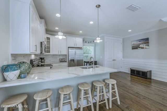 kitchen featuring sink, white cabinetry, decorative light fixtures, appliances with stainless steel finishes, and kitchen peninsula