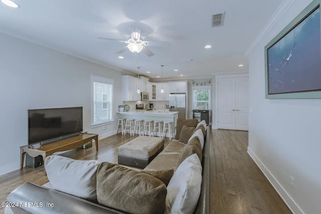 living room featuring plenty of natural light, ornamental molding, and wood-type flooring