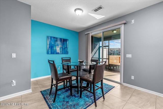 dining room with a textured ceiling and light tile patterned flooring