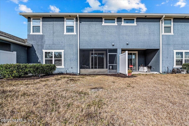 rear view of property featuring a sunroom and a lawn