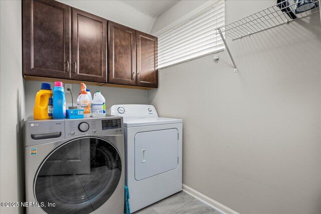 laundry room featuring light tile patterned floors, washing machine and dryer, and cabinets