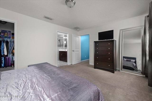 bedroom with ensuite bath, light colored carpet, a textured ceiling, and a closet