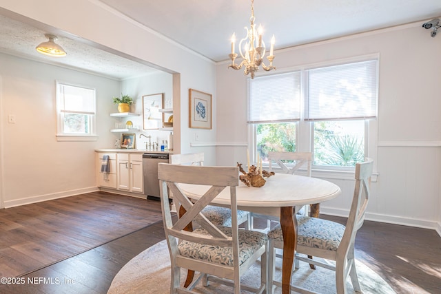 dining room featuring sink, an inviting chandelier, a textured ceiling, ornamental molding, and dark hardwood / wood-style floors