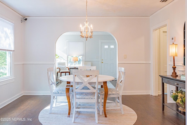 dining space with dark hardwood / wood-style flooring, ornamental molding, and an inviting chandelier