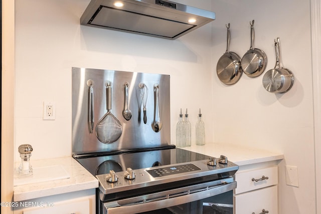 kitchen featuring stainless steel range with electric stovetop, light stone countertops, exhaust hood, and white cabinets