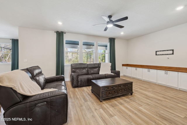 living room featuring a textured ceiling, ceiling fan, and light hardwood / wood-style flooring