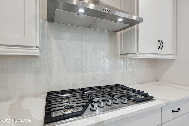 kitchen with white cabinetry, light stone counters, stainless steel gas cooktop, and wall chimney exhaust hood