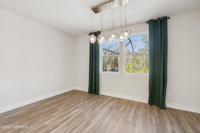 unfurnished dining area featuring light hardwood / wood-style floors and a textured ceiling