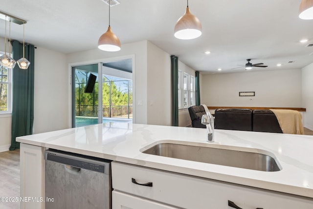 kitchen with sink, white cabinetry, light stone counters, decorative light fixtures, and stainless steel dishwasher