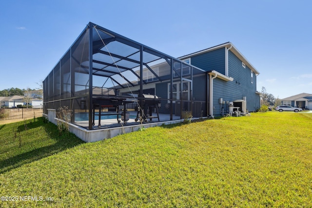 rear view of property featuring a lawn and glass enclosure