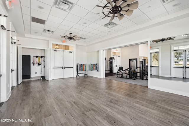 gym with hardwood / wood-style flooring, a drop ceiling, and ceiling fan