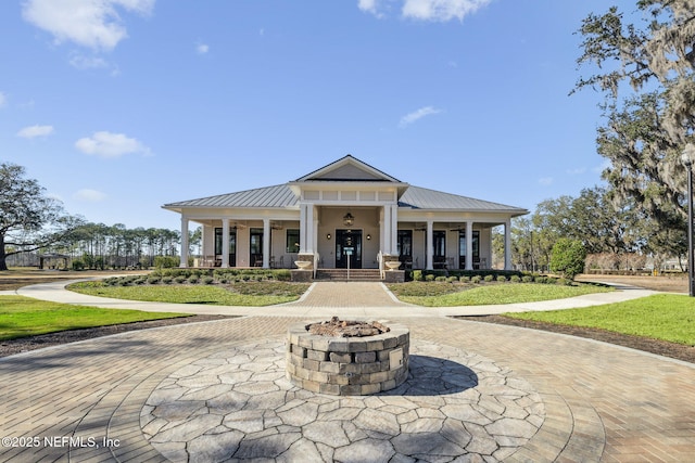 view of front facade featuring covered porch, a front lawn, and an outdoor fire pit