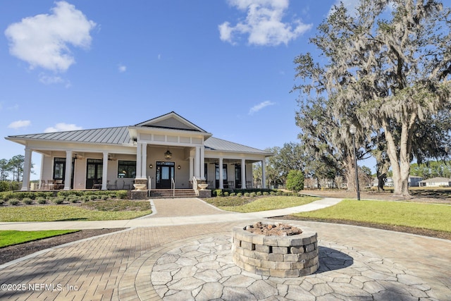 view of front of home featuring a front lawn, covered porch, and a fire pit