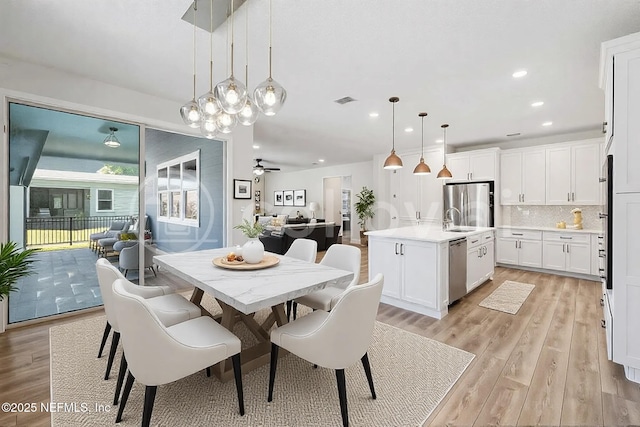 dining room featuring sink, ceiling fan, and light hardwood / wood-style flooring