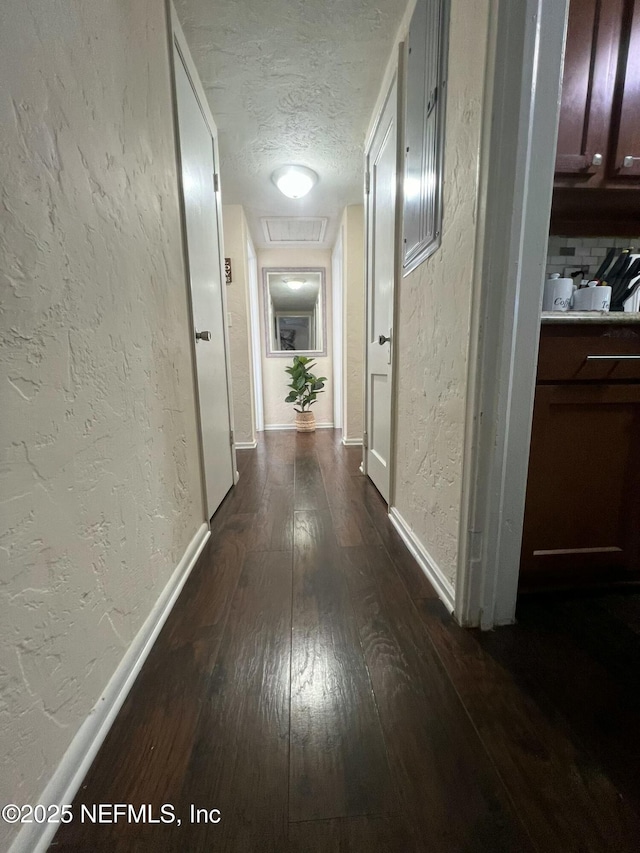 hall featuring dark wood-type flooring and a textured ceiling