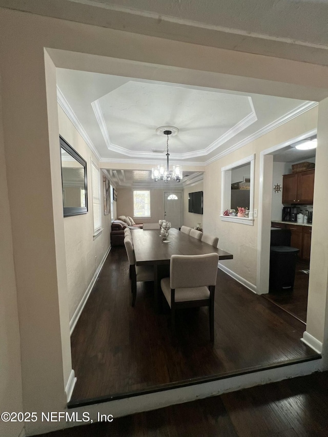 dining space featuring a chandelier, ornamental molding, dark hardwood / wood-style floors, and a raised ceiling