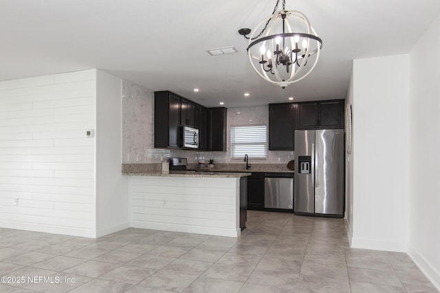 kitchen featuring tasteful backsplash, decorative light fixtures, kitchen peninsula, stainless steel appliances, and light stone countertops