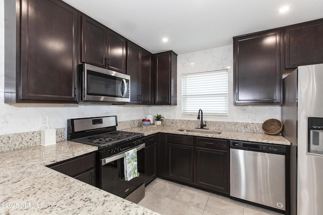 kitchen featuring appliances with stainless steel finishes, sink, light stone counters, and dark brown cabinets