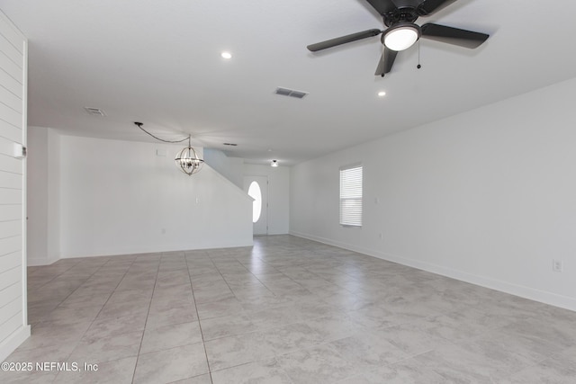 unfurnished room with ceiling fan with notable chandelier