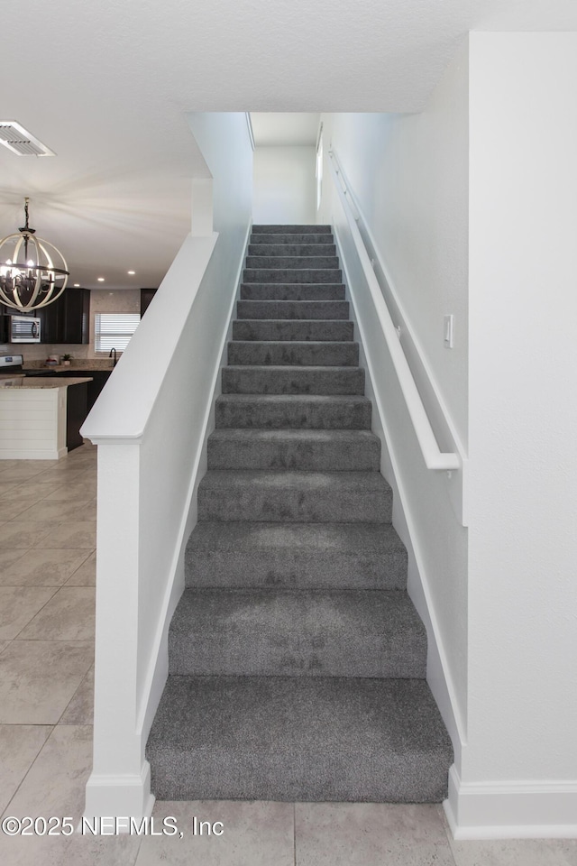 stairs featuring tile patterned floors and a chandelier