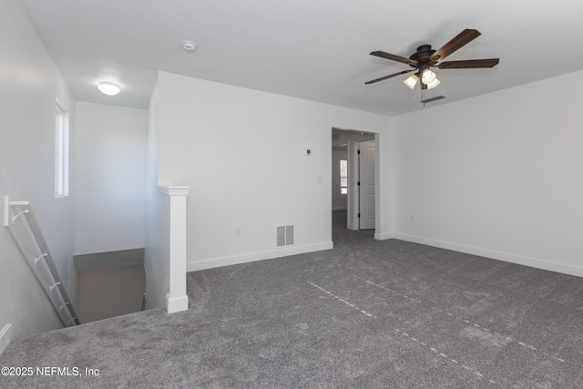 empty room featuring a healthy amount of sunlight, dark carpet, and ceiling fan