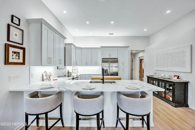 kitchen featuring a breakfast bar area, light hardwood / wood-style flooring, appliances with stainless steel finishes, gray cabinetry, and kitchen peninsula