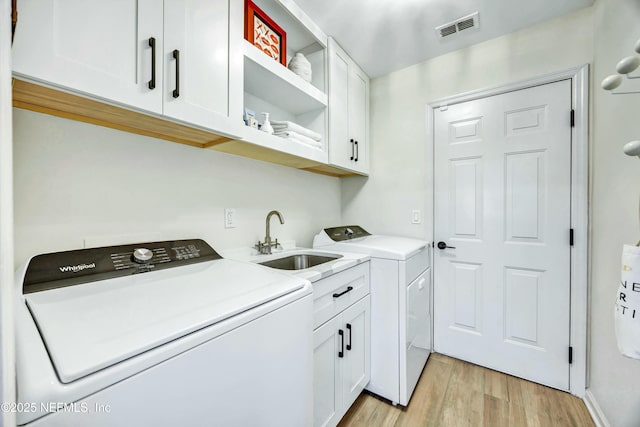 washroom featuring cabinets, sink, independent washer and dryer, and light hardwood / wood-style floors