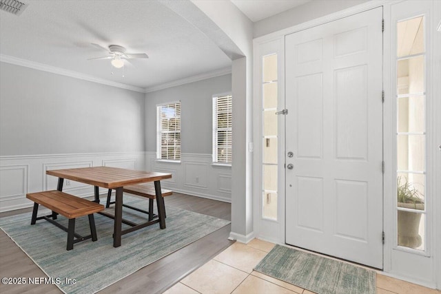 foyer featuring light tile patterned floors, a textured ceiling, ornamental molding, and ceiling fan