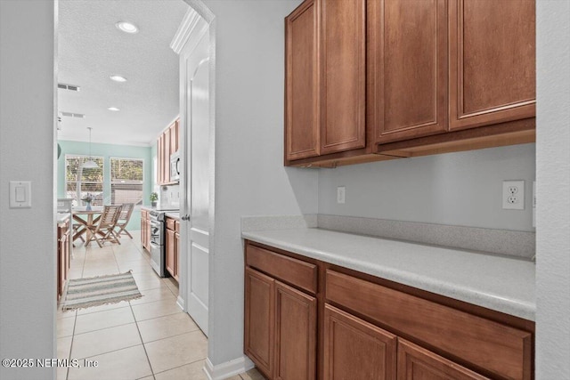 kitchen with light tile patterned floors, decorative light fixtures, stainless steel appliances, and a textured ceiling