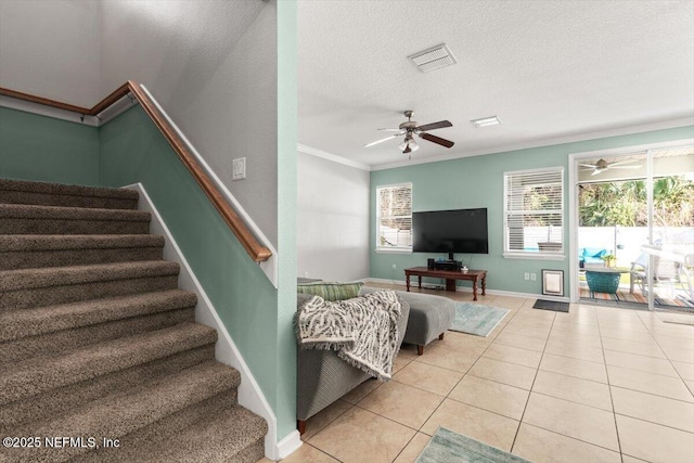 living room featuring ceiling fan, ornamental molding, a textured ceiling, and light tile patterned floors