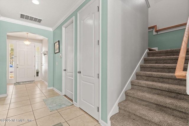 entryway with ornamental molding and light tile patterned flooring