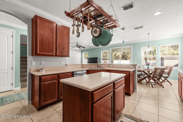 kitchen featuring crown molding, hanging light fixtures, a kitchen island, stainless steel dishwasher, and kitchen peninsula