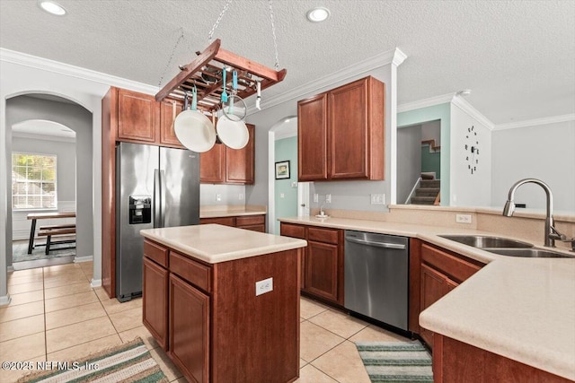 kitchen featuring appliances with stainless steel finishes, sink, a center island, light tile patterned floors, and crown molding