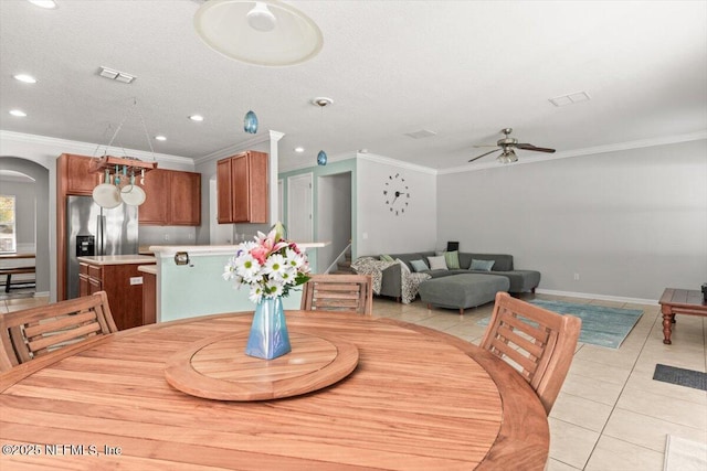 dining room featuring light tile patterned floors, crown molding, a textured ceiling, and ceiling fan