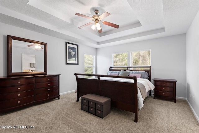 bedroom featuring ceiling fan, a raised ceiling, light carpet, and a textured ceiling