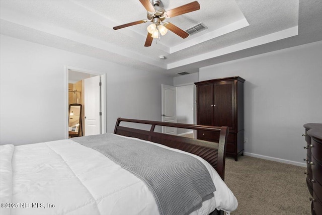 bedroom with ceiling fan, light colored carpet, a textured ceiling, and a tray ceiling