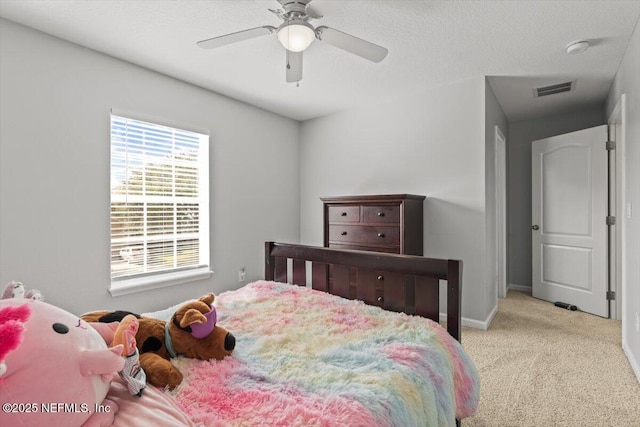 bedroom featuring ceiling fan, light carpet, and a textured ceiling