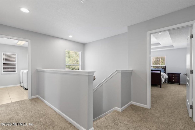 hallway featuring a healthy amount of sunlight, light carpet, and a textured ceiling